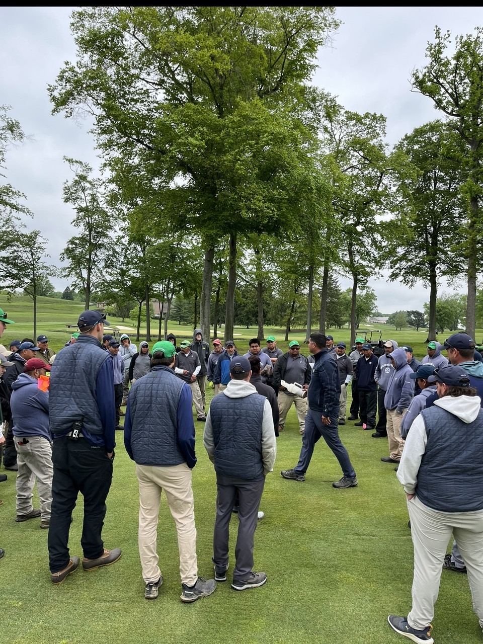 Staff gathered in a circle on the golf course during a training session