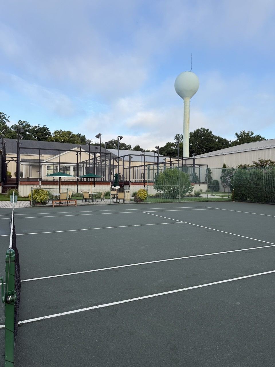 Tennis courts and platform tennis courts with seating area and water tower in the background