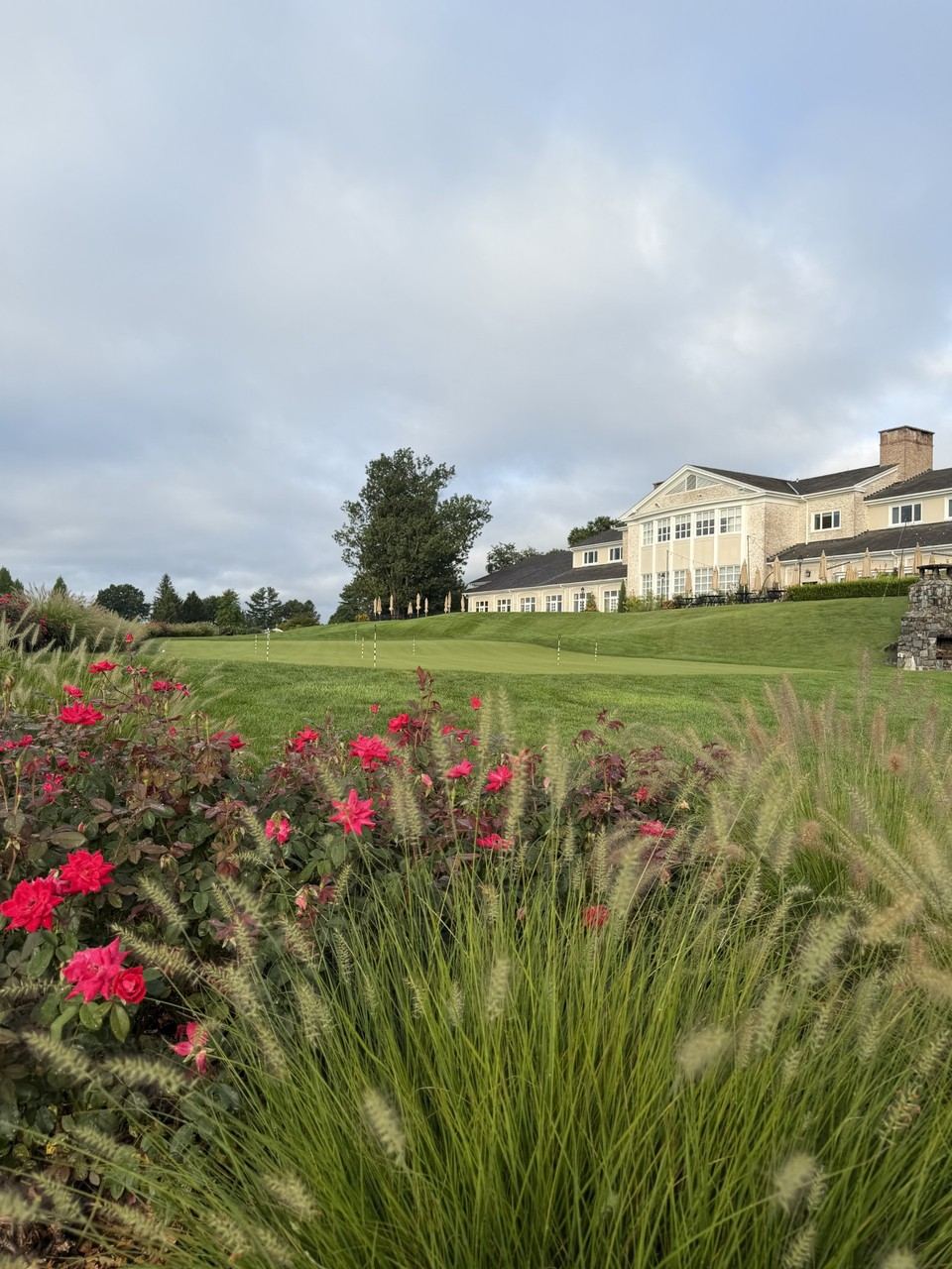 The clubhouse framed by seasonal rose plantings, with a putting green in the foreground