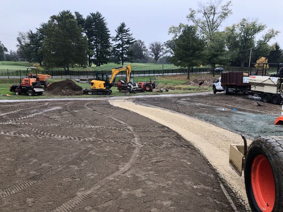 Cart path base construction with drainage work and equipment staged nearby