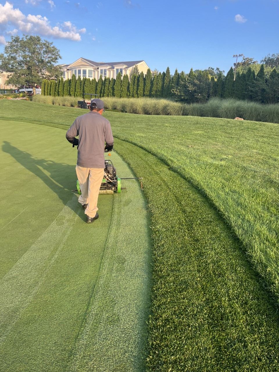 Superintendent mowing a precise collar line beside a green