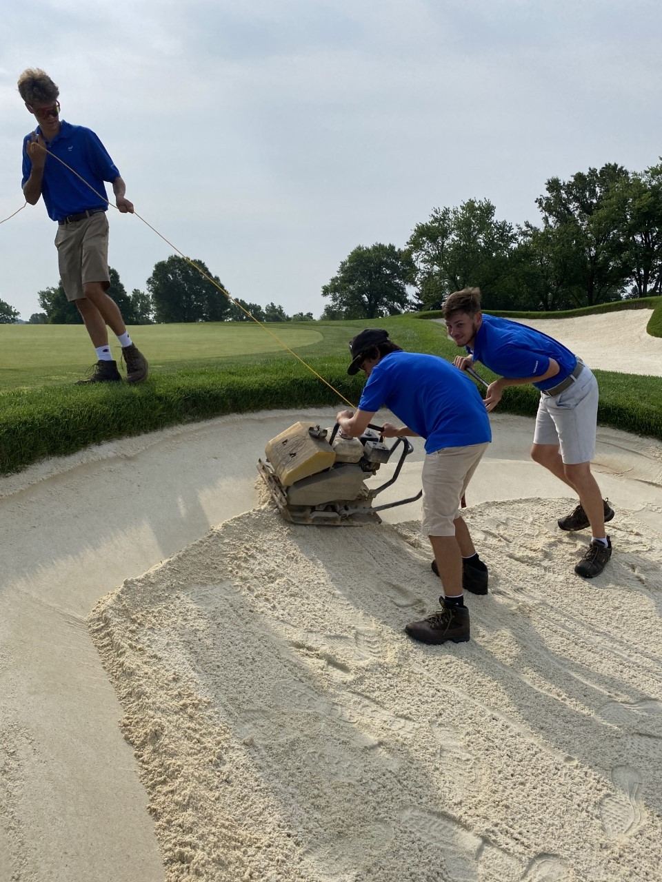 Crew using a plate tamper to compact a bunker face